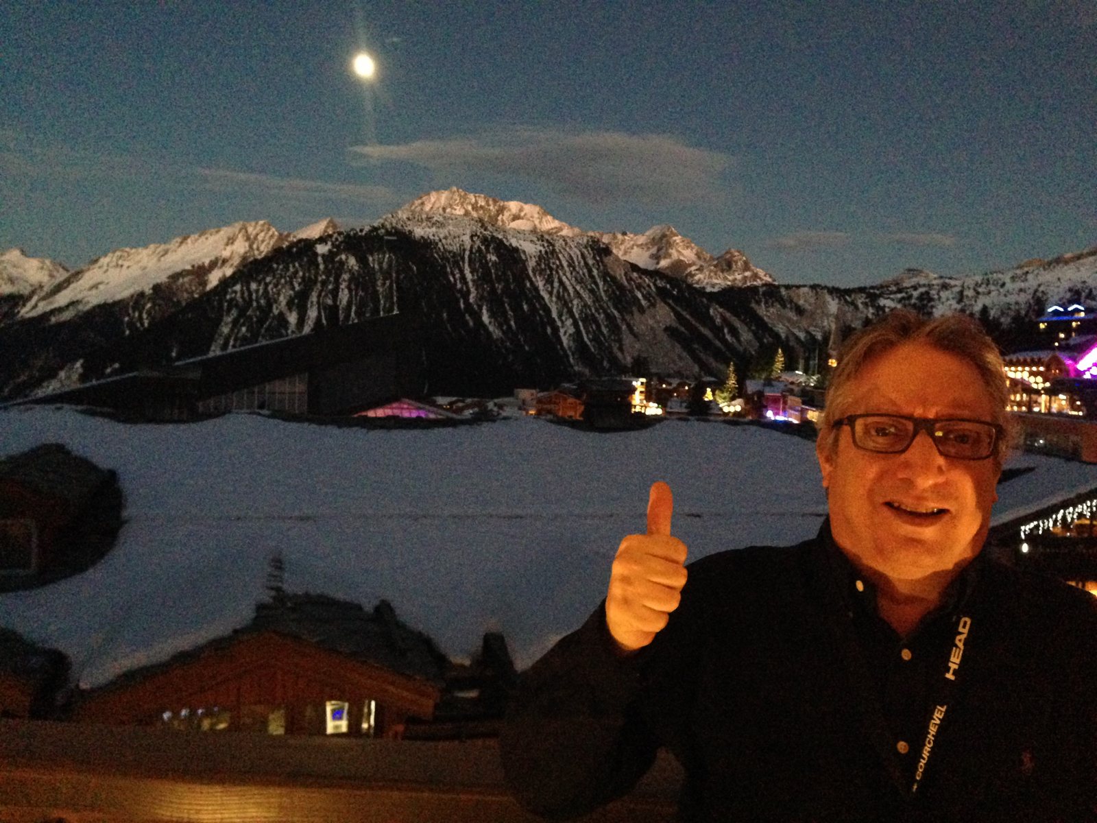 Giora en una terraza de Courchevel al anochecer, con la luna sobre las montañas