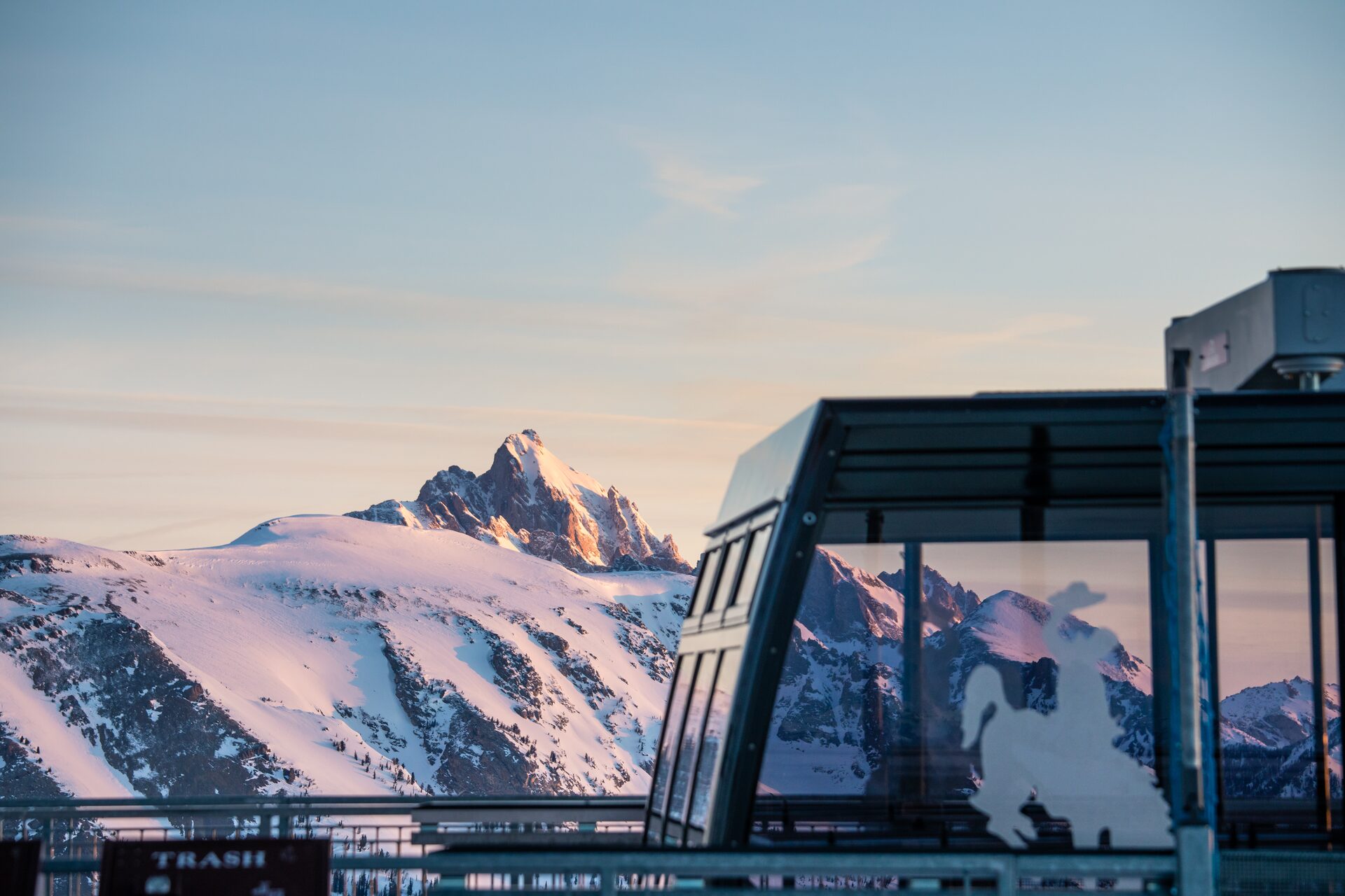 Un pico afilado de los Tetons con luz rosada, junto a la estación superior acristalada del teleférico