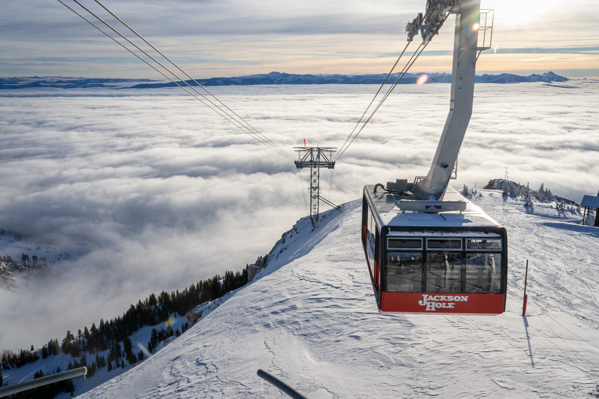 La cabina del teleférico llega a la cima nevada con el valle cubierto por un mar de nubes