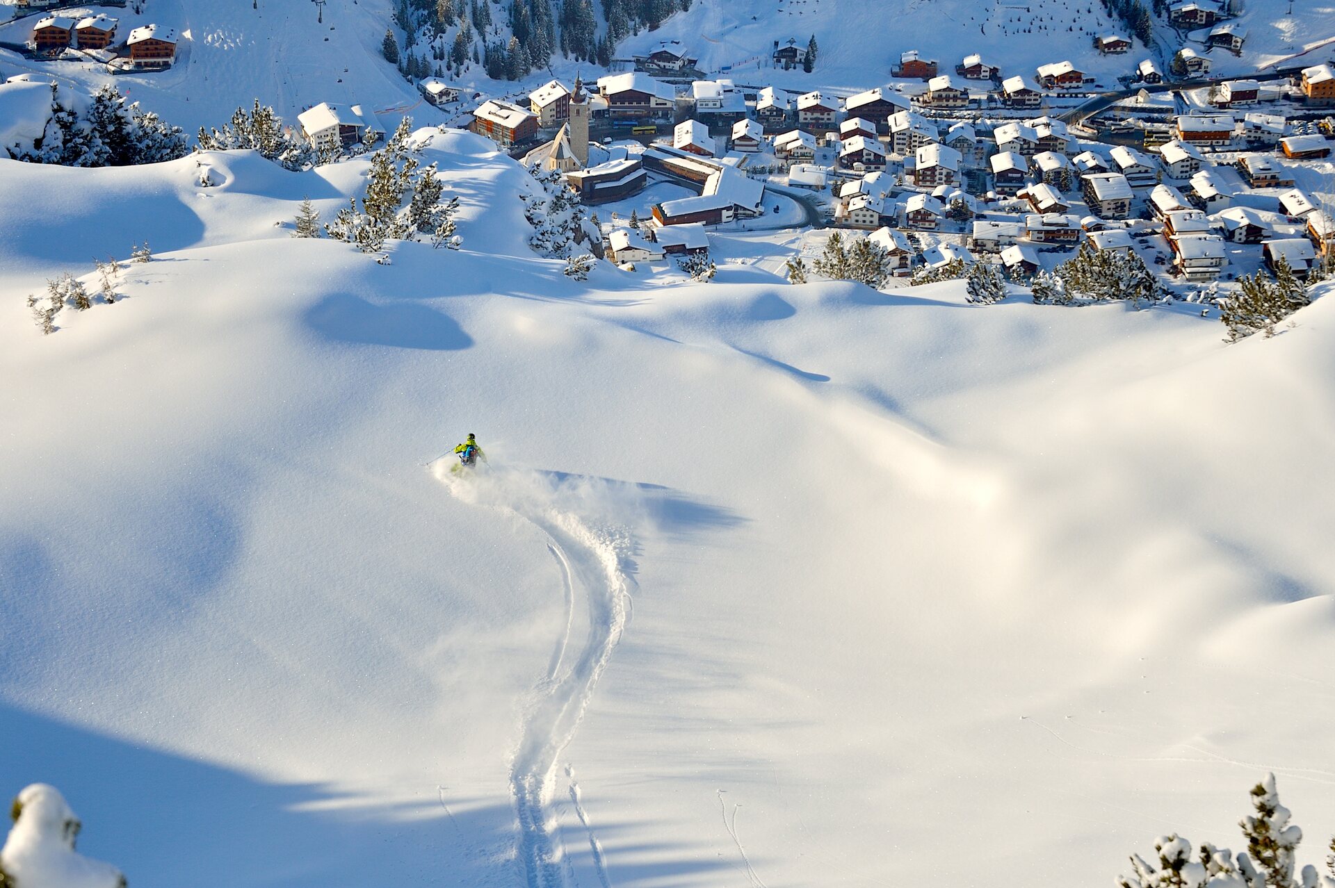 Un esquiador traza una huella en nieve virgen sobre los tejados nevados del pueblo de Lech