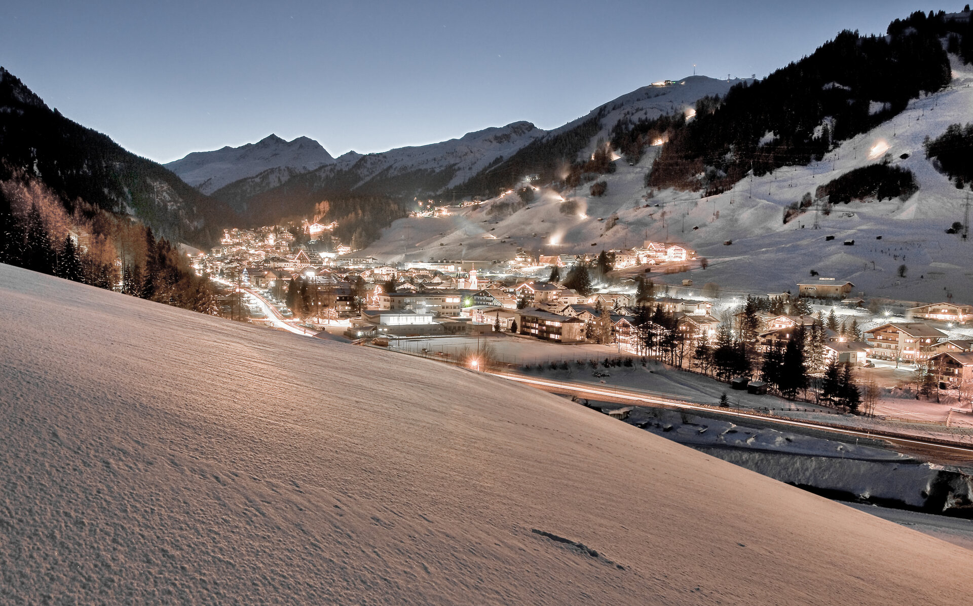 St. Anton am Arlberg nevado al anochecer, con el pueblo iluminado